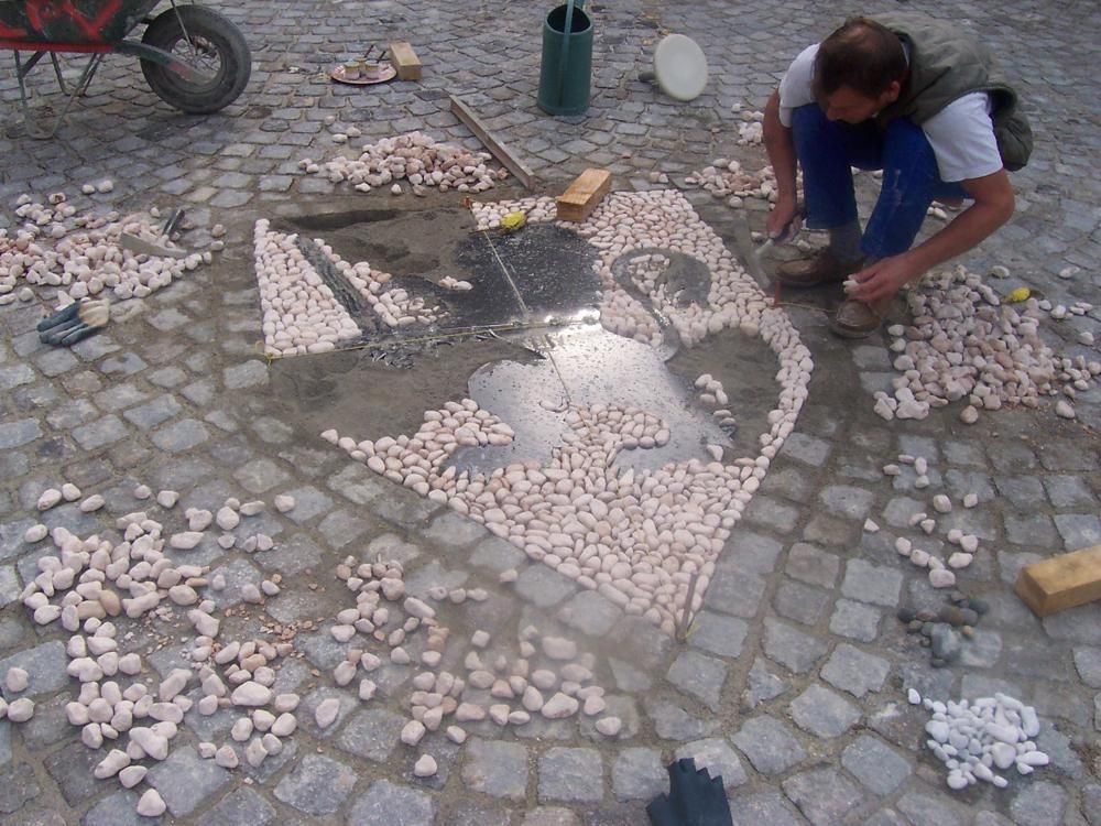 Pose des galets pour concevoir un blason en galets naturels par Loreto Pavage